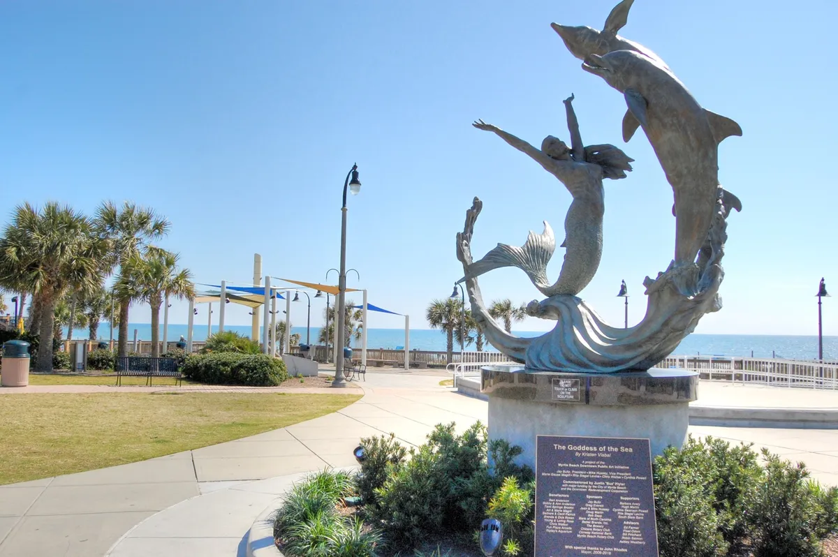 A picturesque scene of a bronze mermaid and dolphins statue set against an ocean view and palm trees. The setting conveys a sense of playful tranquility and the coastal charm that defines the resort's atmosphere.